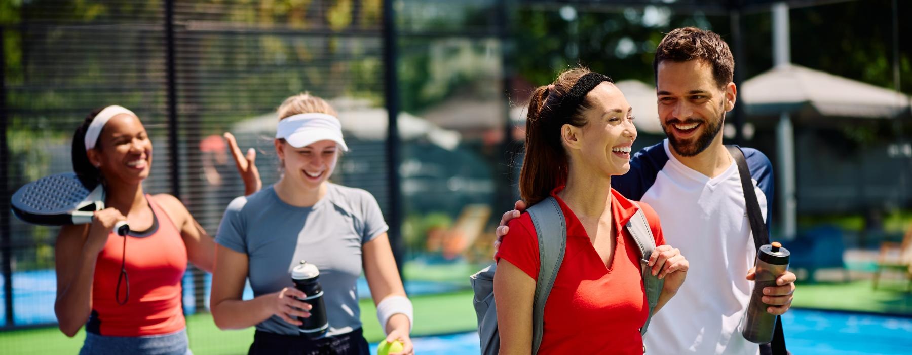 a group of people stand around a tennis court
